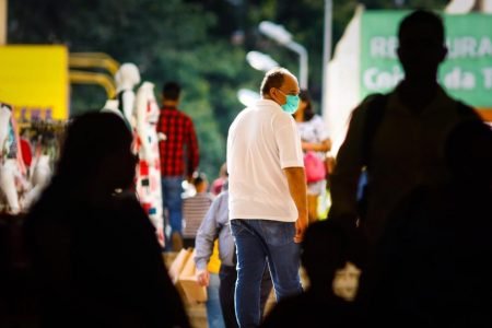 Homem de camisa branca usa máscara na rua contra o coronavírus