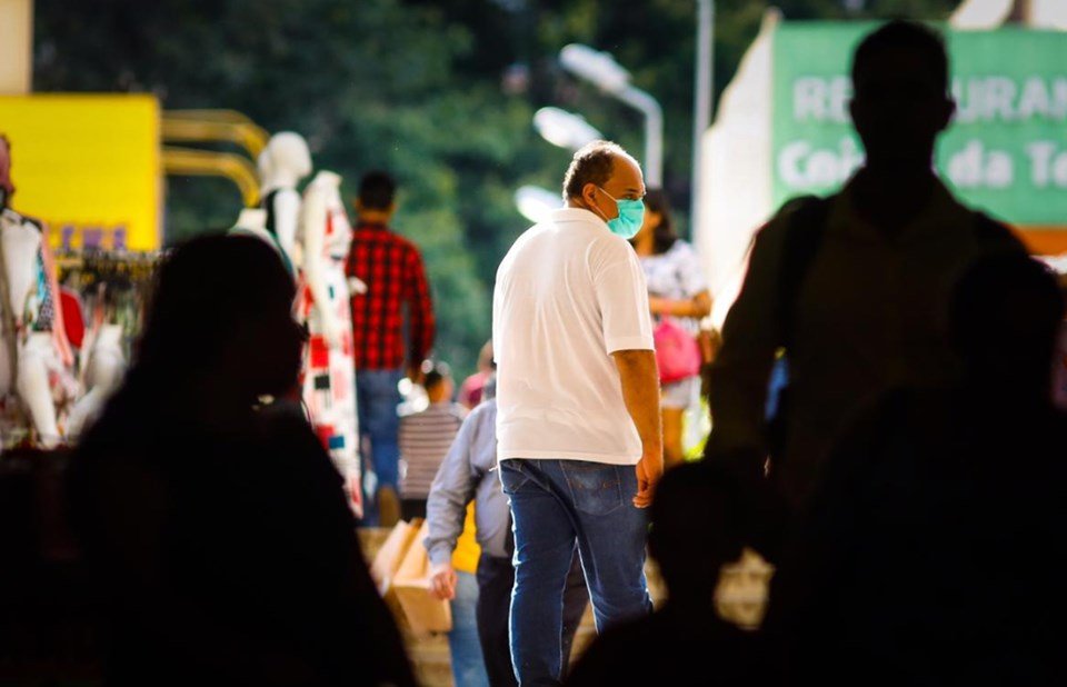 Homem de camisa branca usa máscara na rua contra o coronavírus