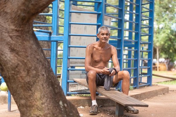 Homem sem camisa sentado em ponto de exercício comunitário
