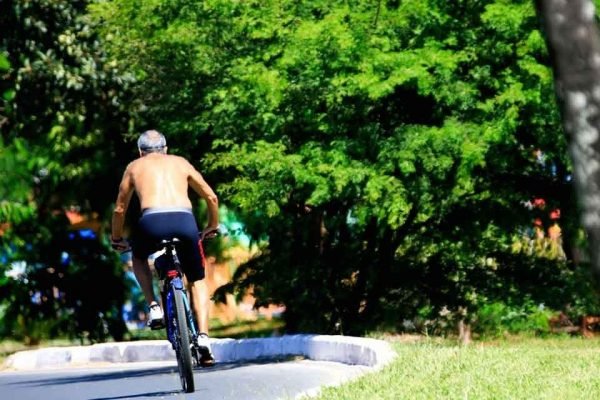 Homem sem camisa andando de bicicleta em parque