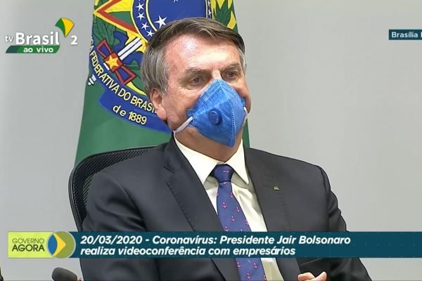 Presidente Jair Bolsonaro, de máscara, em videoconferência com empresários