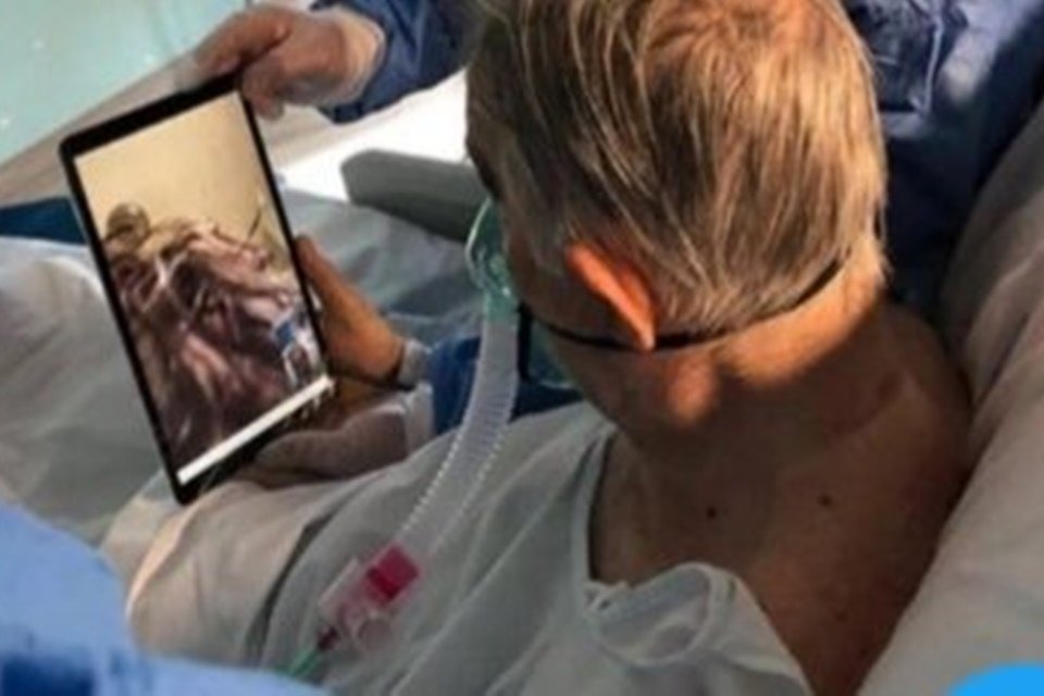 Homem acamado olhando tablet