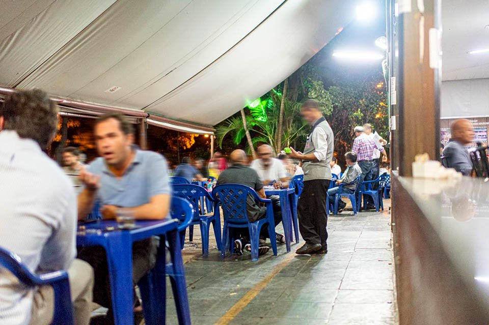 Garçon atende mesa em aos clientes no bar