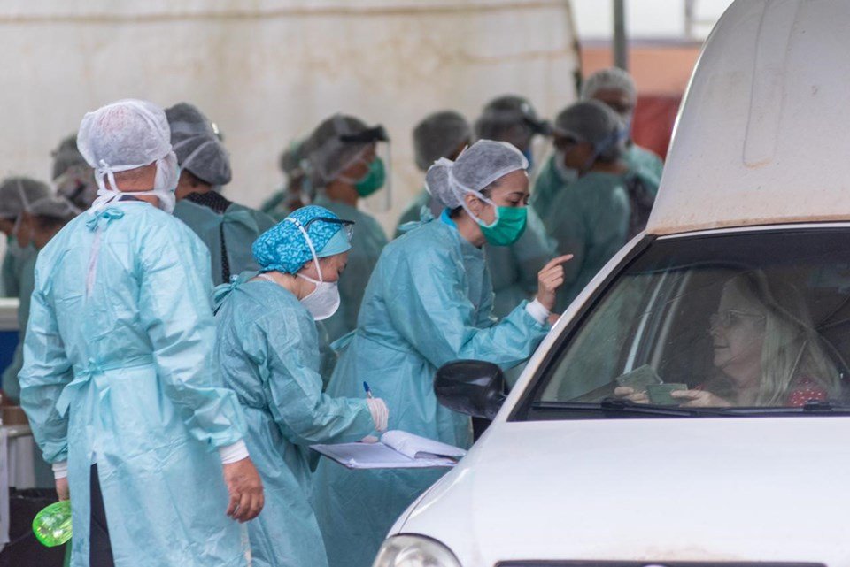 Carro branco parado ao lado de enfermeiros
