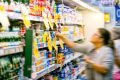 mulher faz escolhe de produtos em pratilheira de supermercados