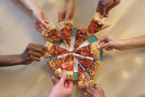 Mãos pegando fatias de pizza