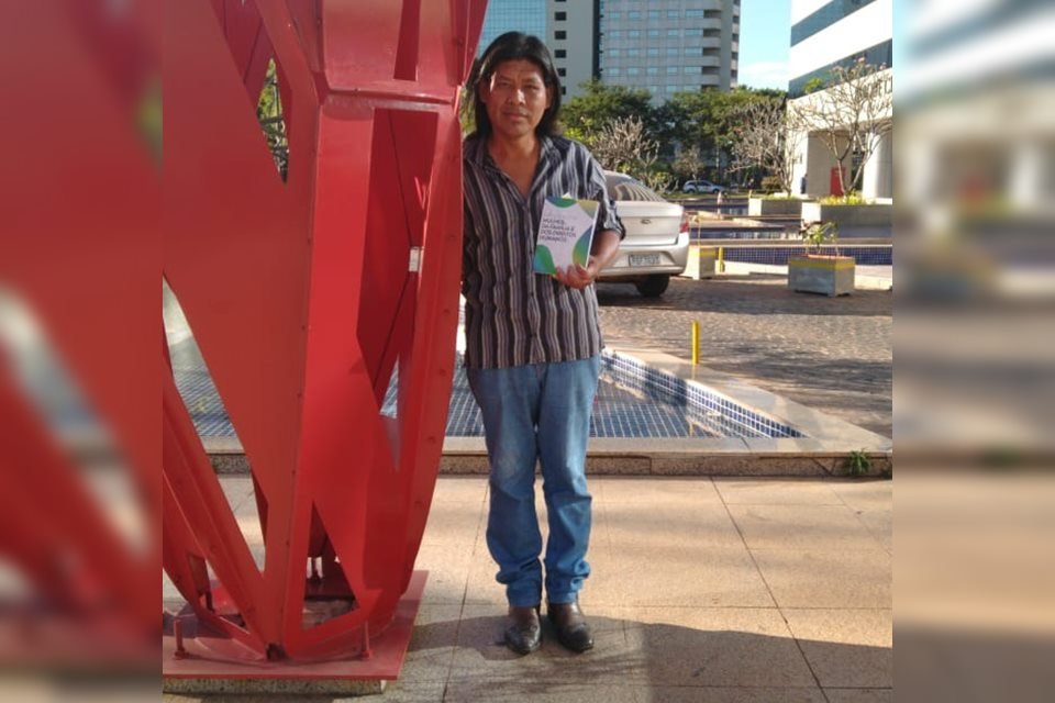 Homem ao lado de escultura segurando livro