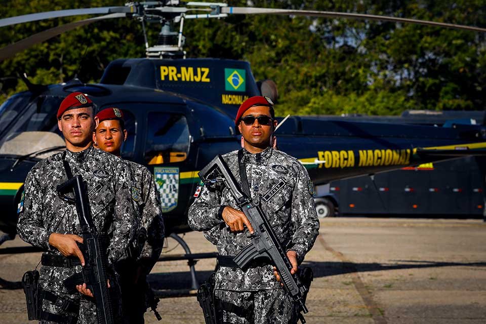 Soldados da força nacional com helicoptero ao fundo
