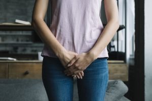 Mulher com as duas mãos em frente ao órgão sexual