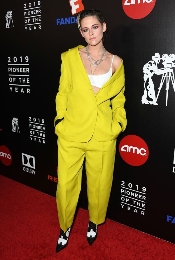 Kristen Stewart com conjunto de alfaiataria amarelo e sutiã à mostra
