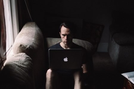 Homem sentado no sofá com computador