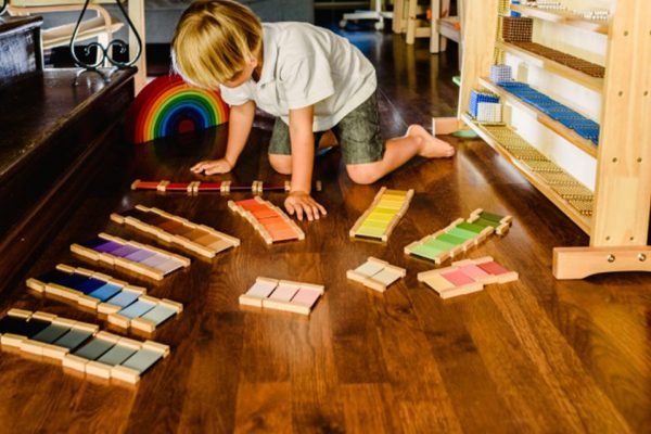 Criança loira brincando no chão com brincadeira montessori