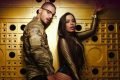 Foto colorida de Anitta e Maluma em fundo dourado - Metrópoles