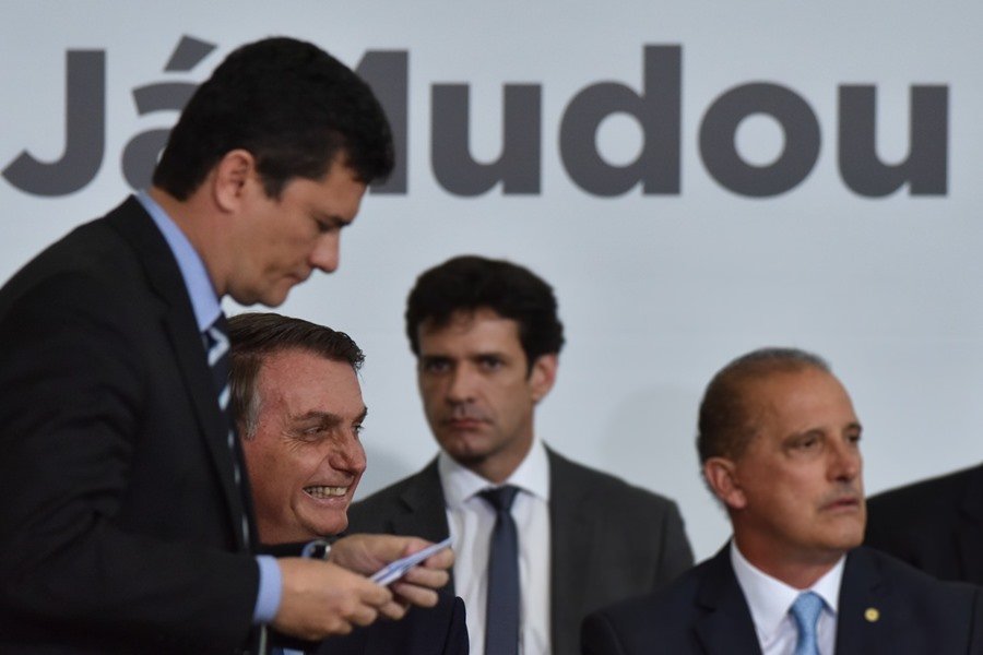 Moro e Bolsonaro em frente a cartaz