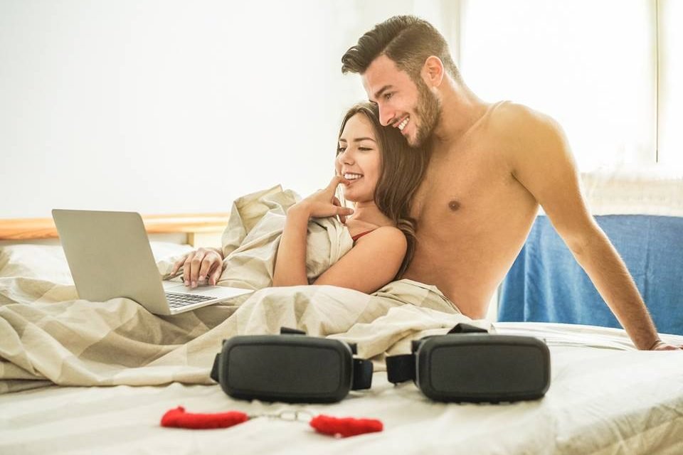 Casal na cama olhando para o notebook