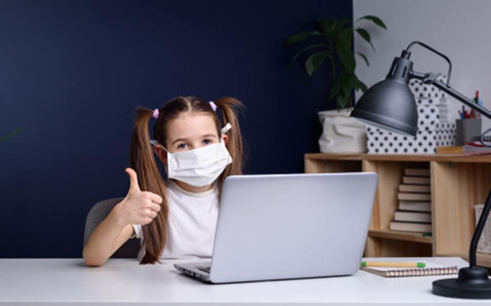 Menina de máscara na frente do computador