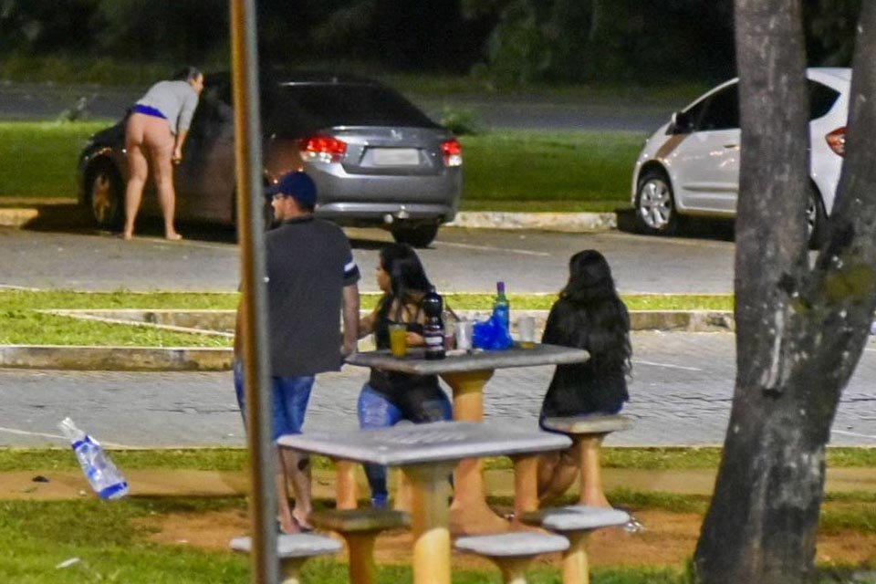 Um homem e duas mulheres com garrafas sobre a mesa de concreto