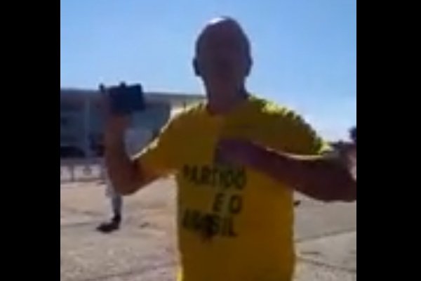 Homem de camisa amarela e celular na mão