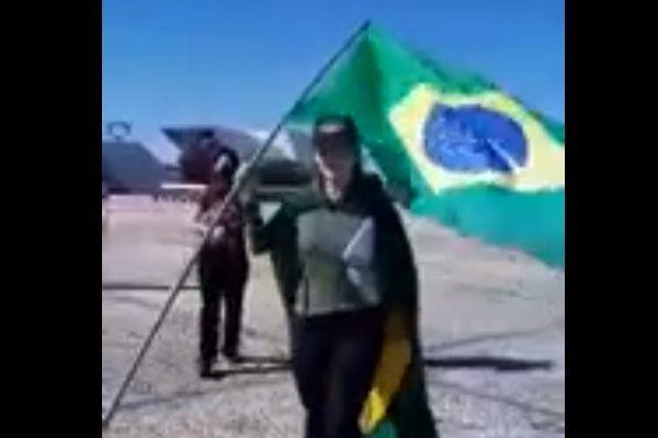 Mulher de boné e bandeira do Brasil na mão