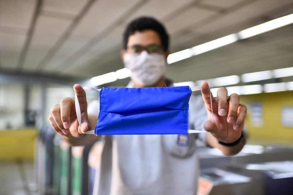 Profissional de saúde segurando uma máscara cirúrgica azul