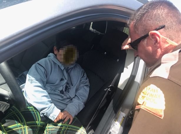 Menino dentro de carro e policial interrogando