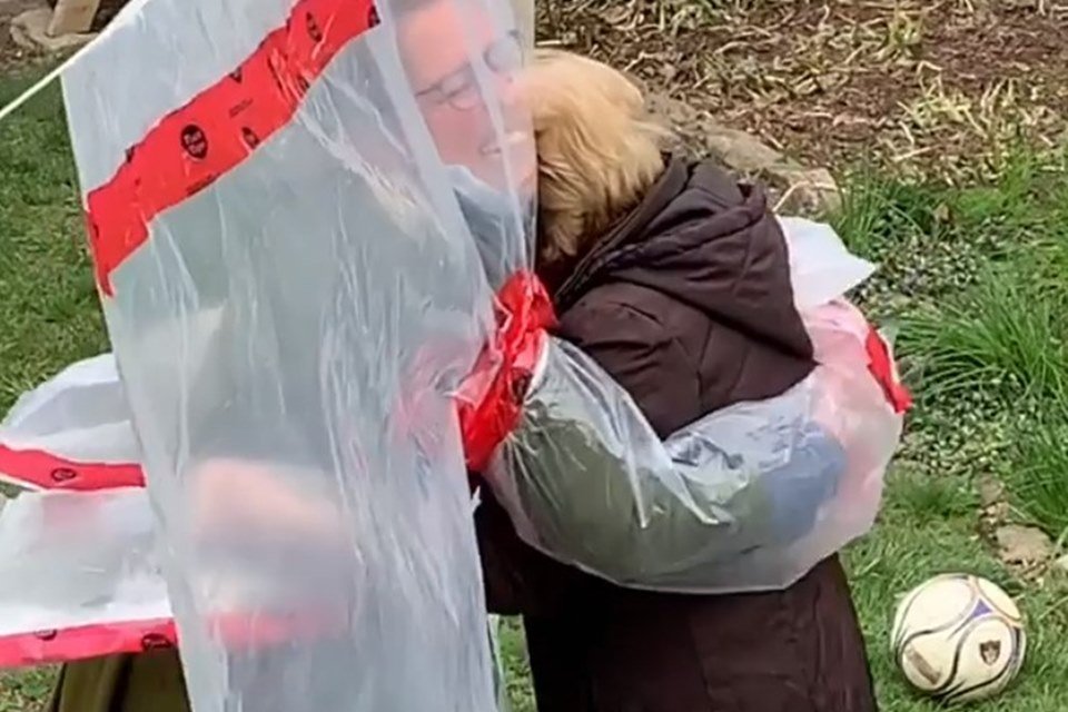 Duas mulheres se abraçando através de um plástico