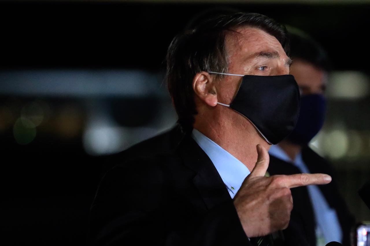 Bolsonaro faz gesto com o dedo indicador, usando máscara da PF