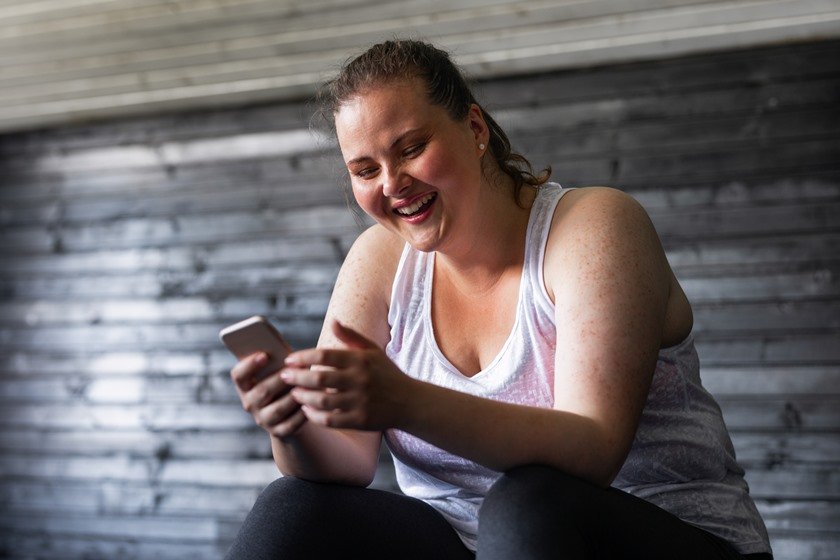 Mulher praticando exercícios com celular na mão