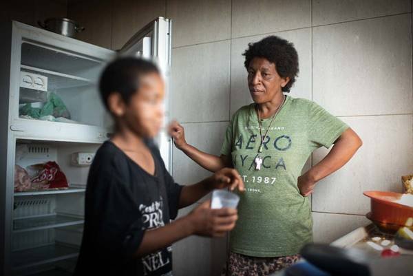 Mulher e menino em frente de geladeira vazia