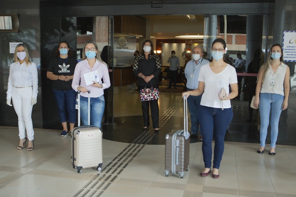 Pessoas com máscaras e malas na entrada do hotel Bittar