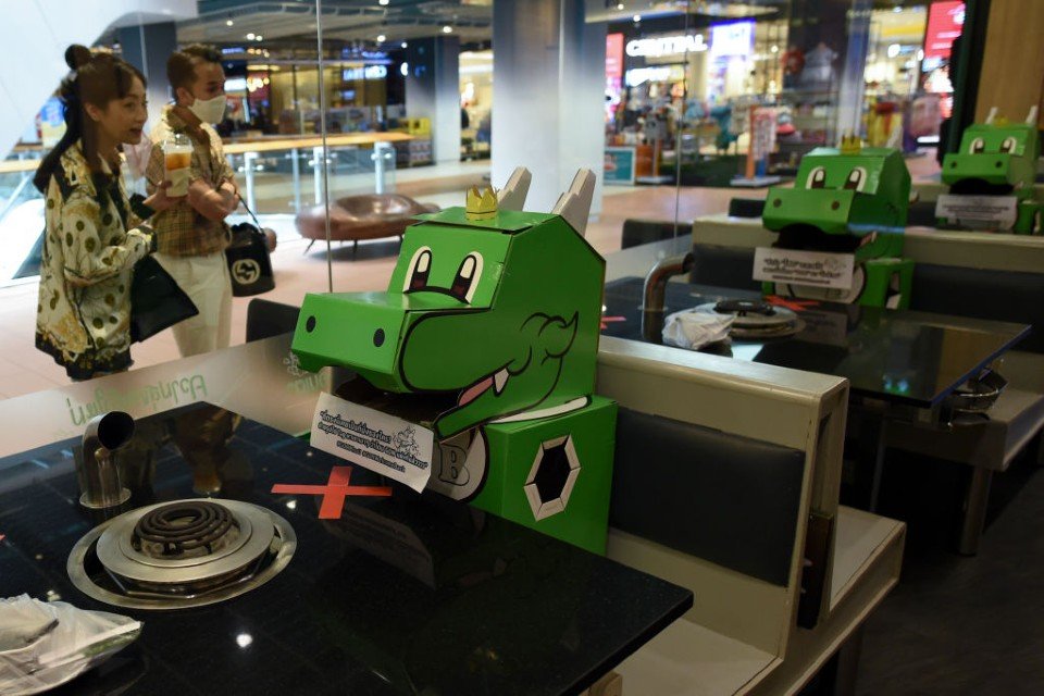 Dinossauros de papelão ocupam espaços em restaurante na Tailândia, para reforçar o distanciamento social
