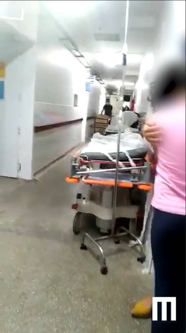 Pessoas e macas no corredor de hospital