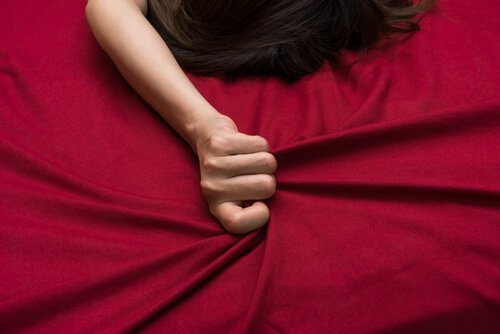 Mão de mulher apertando lençol vermelho