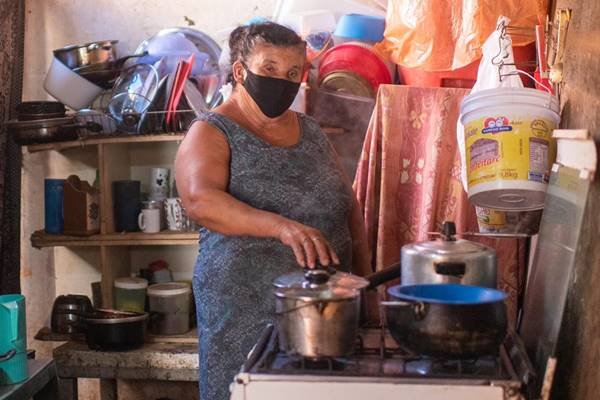 Mulher com máscara na cozinha