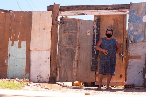 Mulher com máscara em frente de casa