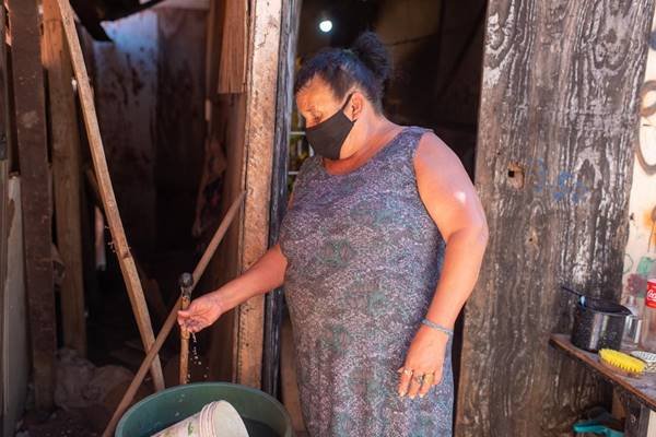 Mulher com máscara lavando as mãos