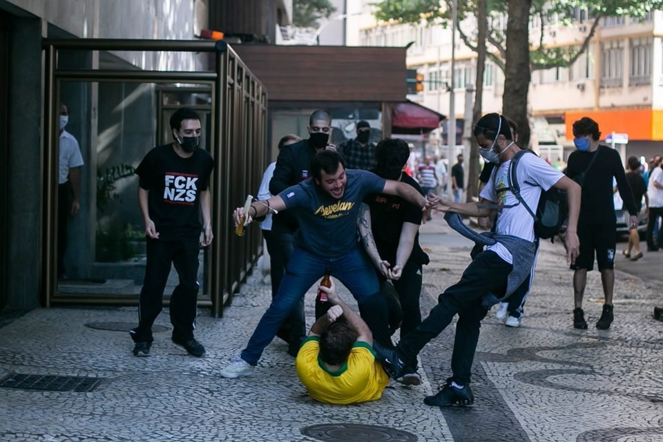 Manifestante com camisa amarela é chutado enquanto está caído