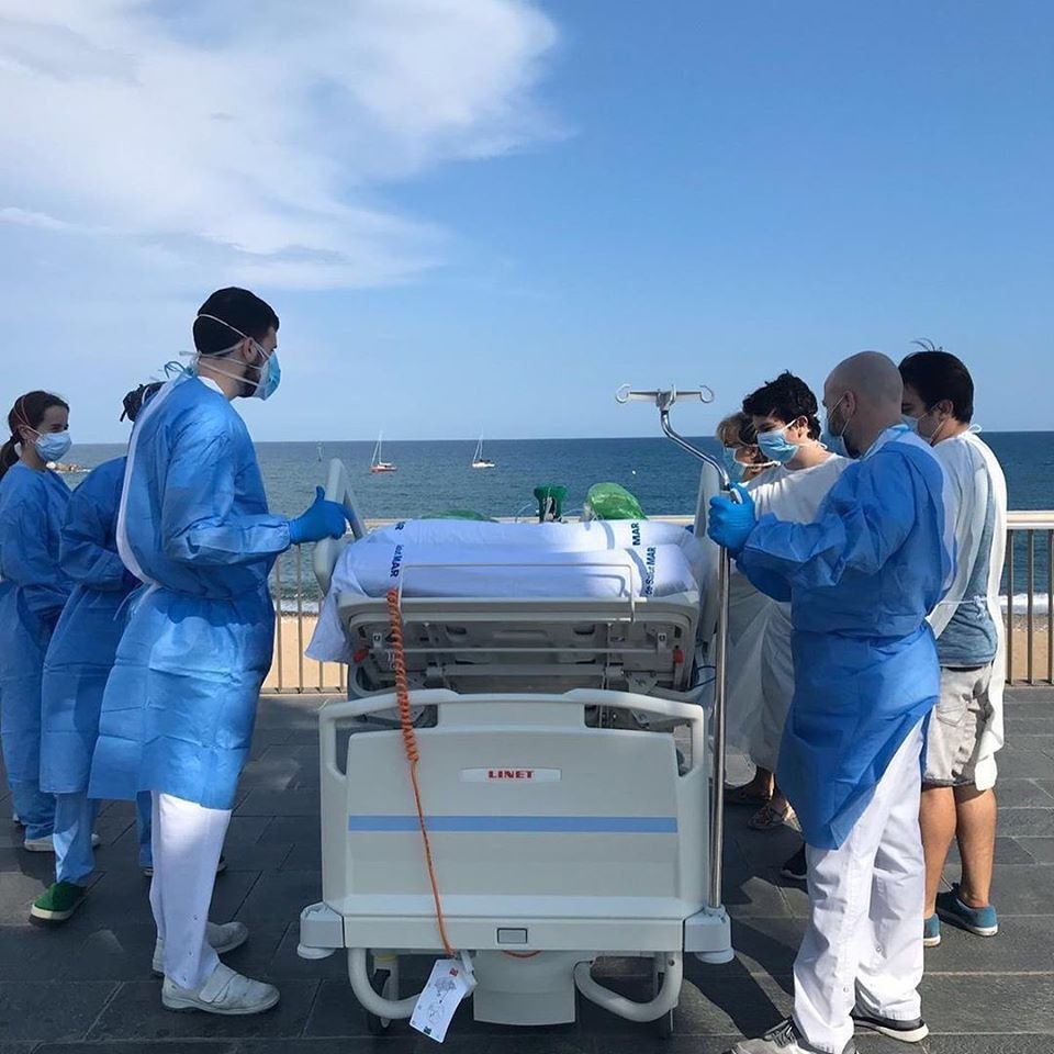 Funcionários levam maca de paciente para orla marítima em Barcelona