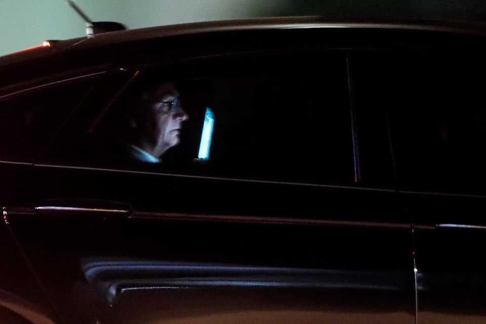 Jair Bolsonaro no banco traseiro do carro, deixando o Palácio do Planalto à noite