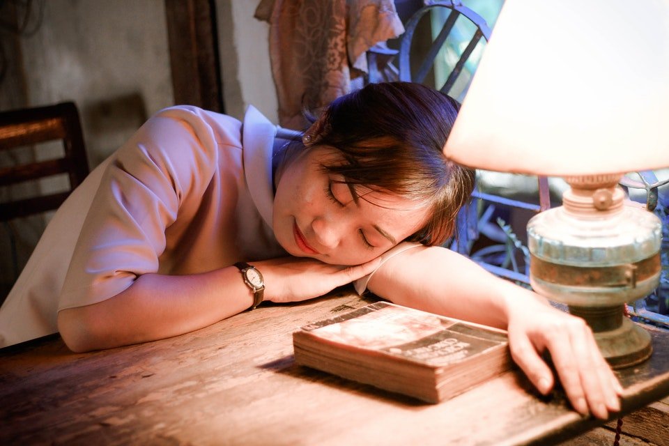 mulher dormindo na mesa com livros
