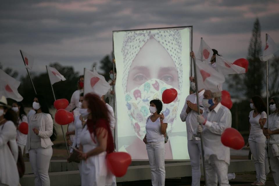 Pessoas de jaleco branco com balões vermelhos