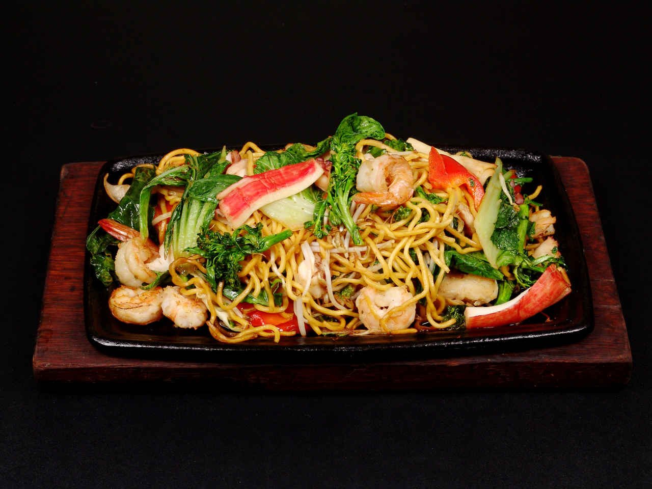 Yakissoba de camarão em prato preto visto de cima