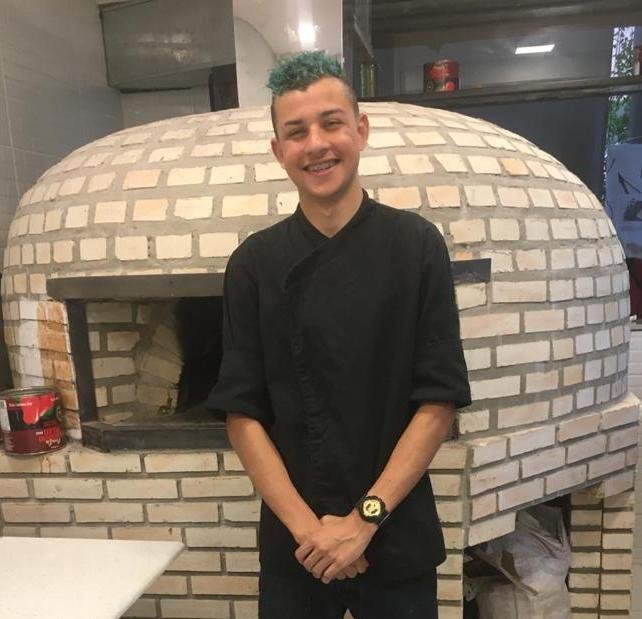 Colaborador em frente a forno de pizza