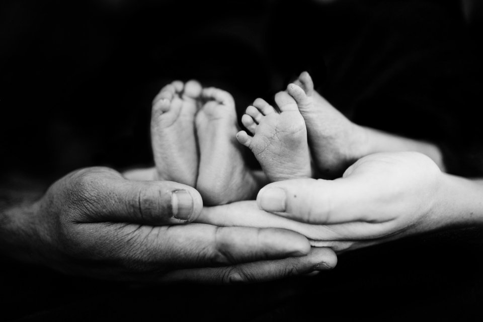 Pai e mãe seguram os pés de bebês gêmeos