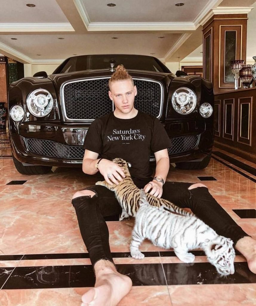 jovem homem em frente a carro de luxo