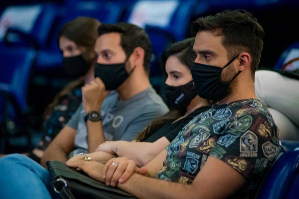 pessoas de máscara sentadas olhando para frente