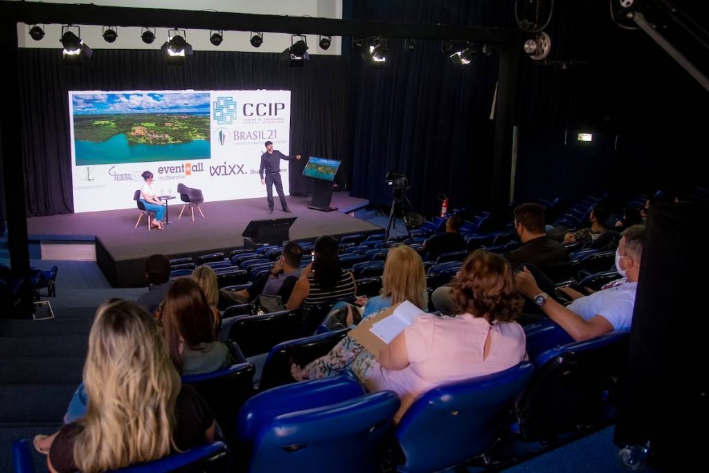 plateia assistindo palestra em palco. homem e mulher no palco