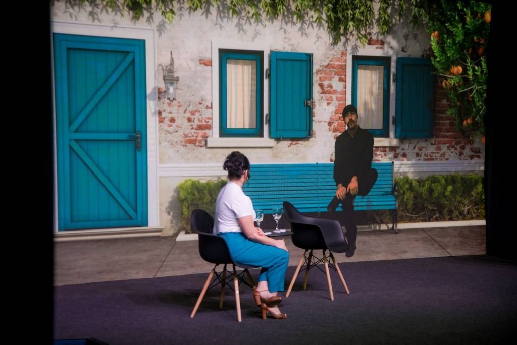 mulher sentada no palco olhando para telão