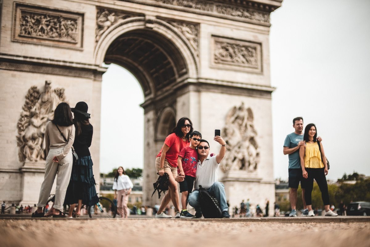 Família tira foto em frente ao Arco do Triunfo, em Paris
