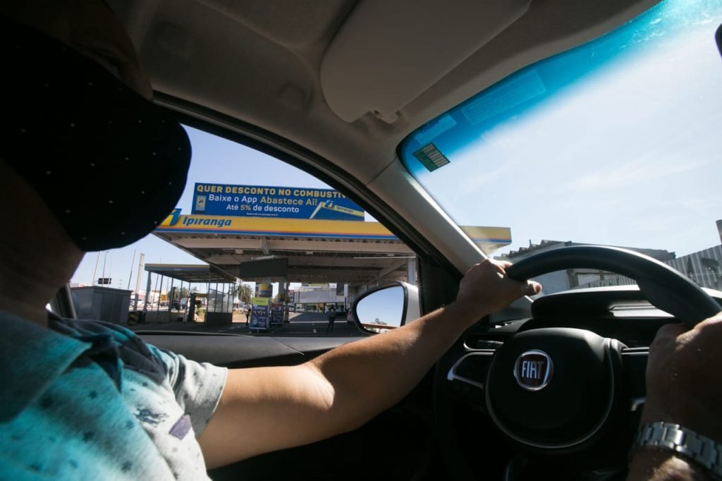 Motorista em frente a posto de combustível